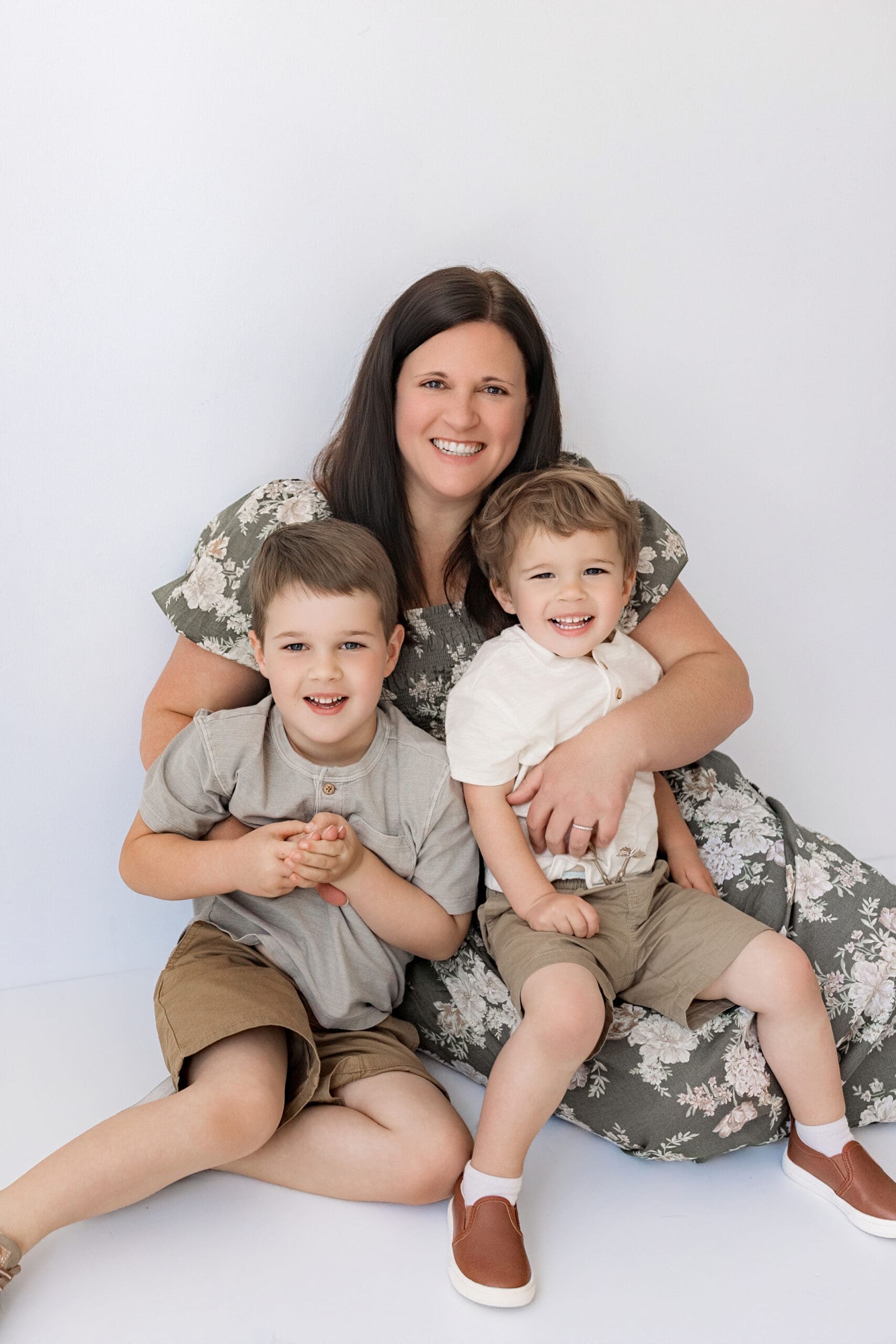 Mother sitting with her two sons in a bright white studio during a natural, candid family photography session