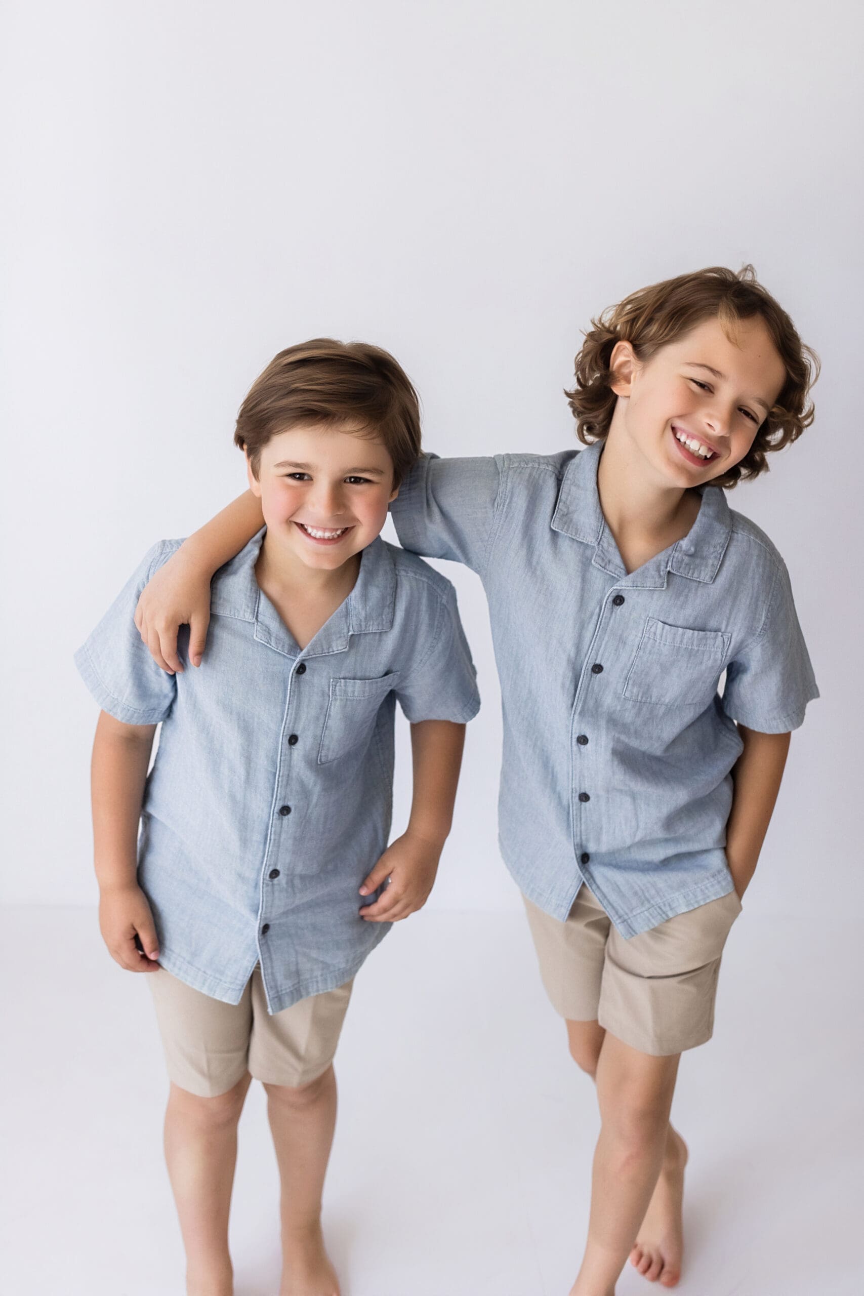 Two brothers in a casual pose sitting together in a studio during a natural family photography session