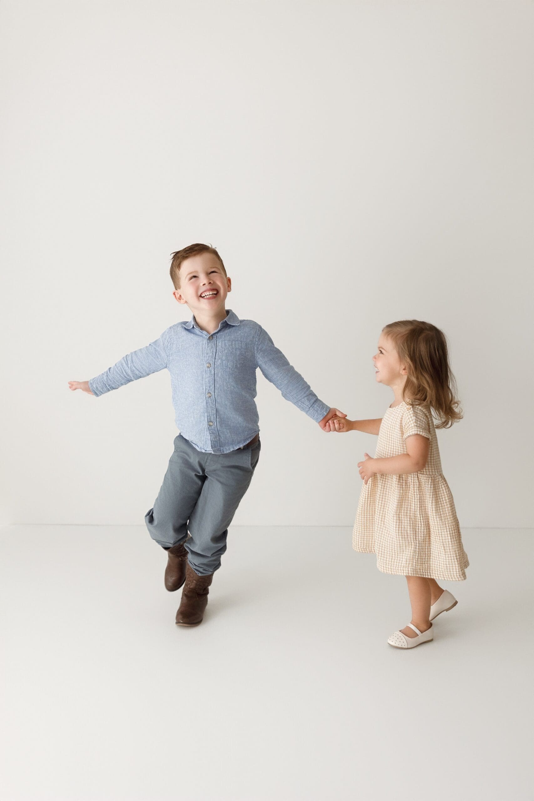 Young brother and sister laughing and playing together during a studio family photography session.