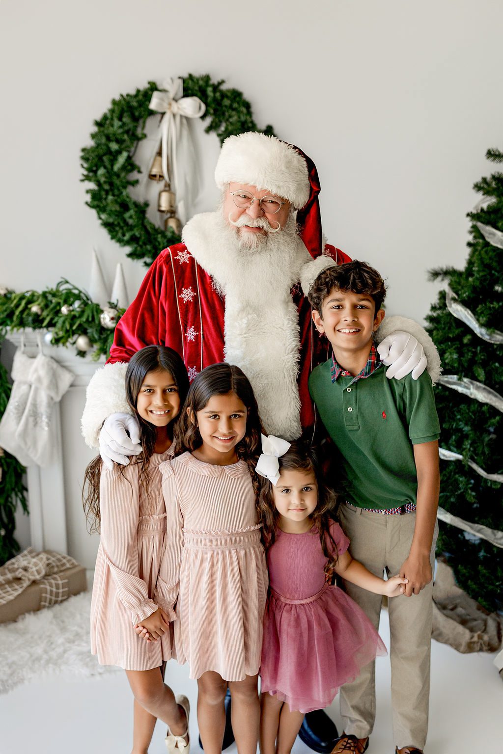 Three children smiling with Santa during a Christmas studio photography session in St. Louis, Missouri