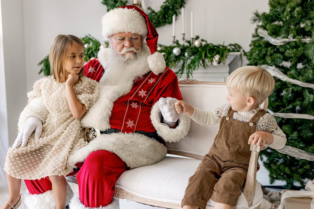 Santa giving two children a high five during a Christmas photo session in St. Louis