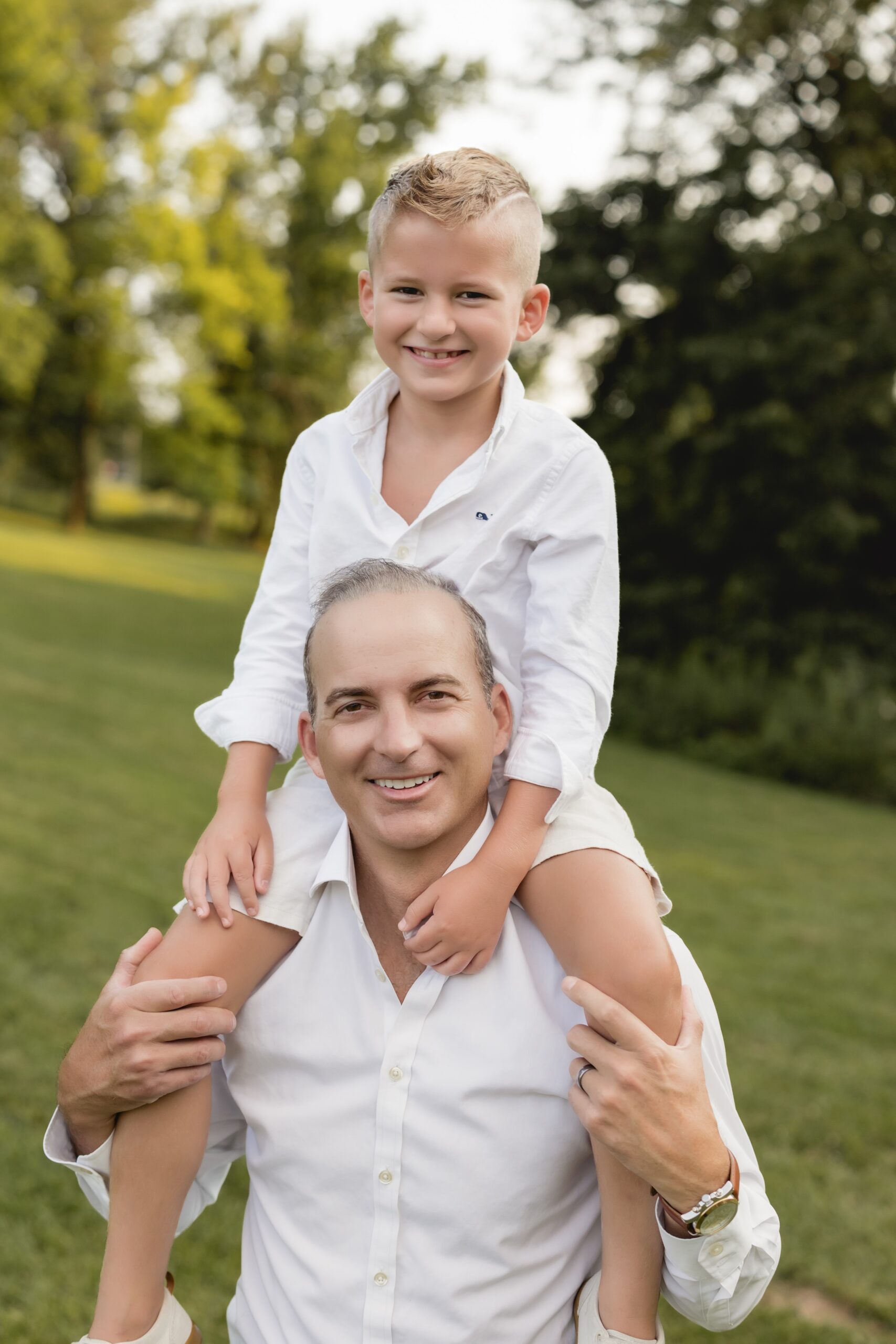 Father carrying his son on his shoulders during a family photography session in a St. Louis park