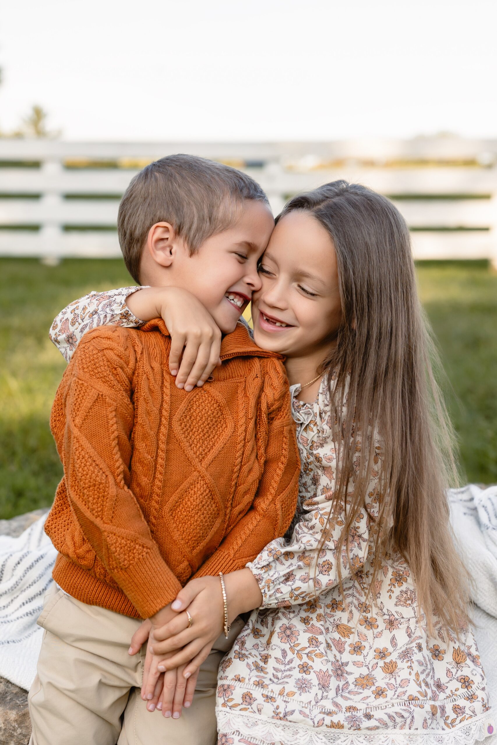 Brother and sister smiling at each other during a family photography session in a St. Louis park.